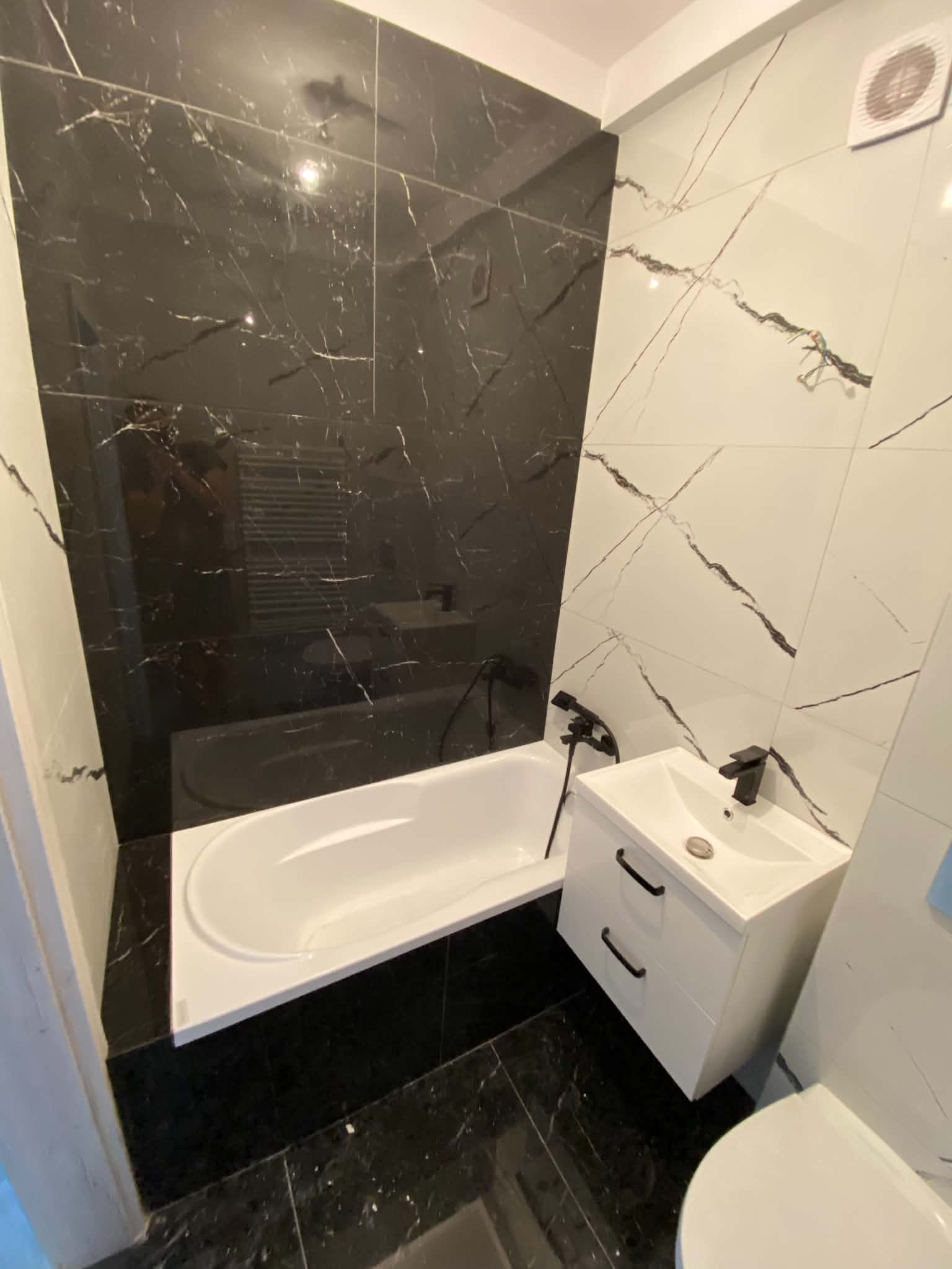 Finished bathroom by Kuzbyt Construction with a dark marble-look feature wall behind the bath