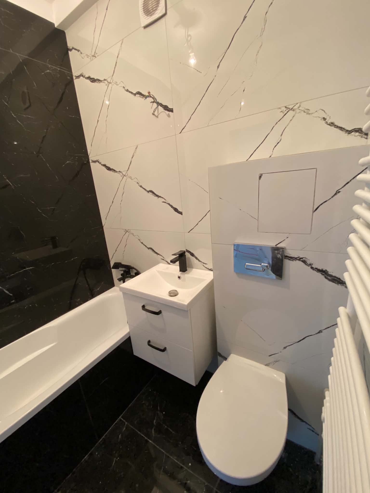 Marble-look tiled bathroom with black tapware, a white vanity unit and a wall-hung toilet